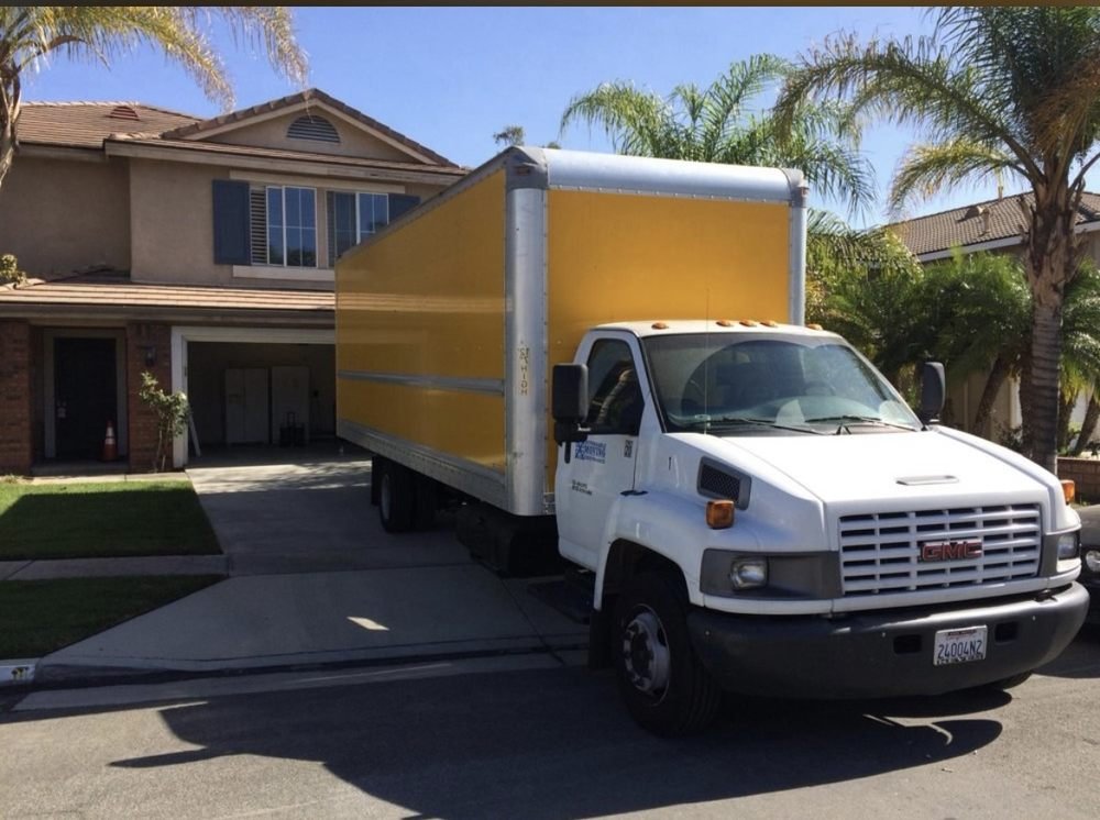 Large yellow and white moving truck in front of a residential home, ready for student moving and packing services in Los Angeles